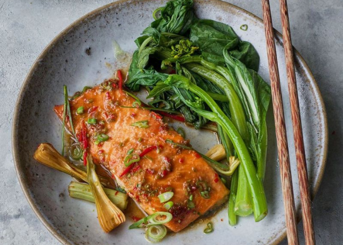 Baked Rainbow Trout Fillet on a Plate with Spring Onions and Coriander Leaves