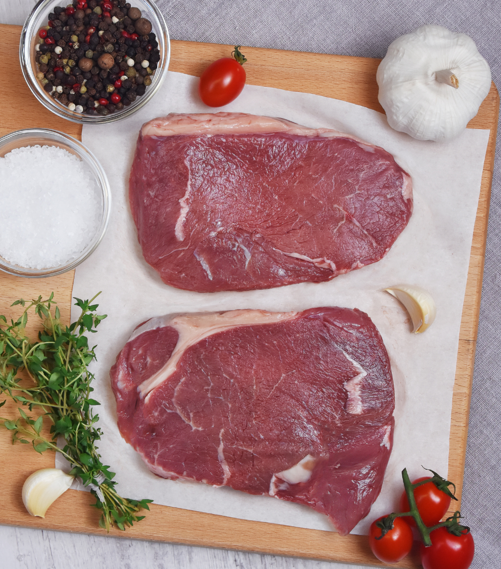 Perfect prime cuts NZ Angus Beef Rump Steak with red grape tomato, garlic and spices by side