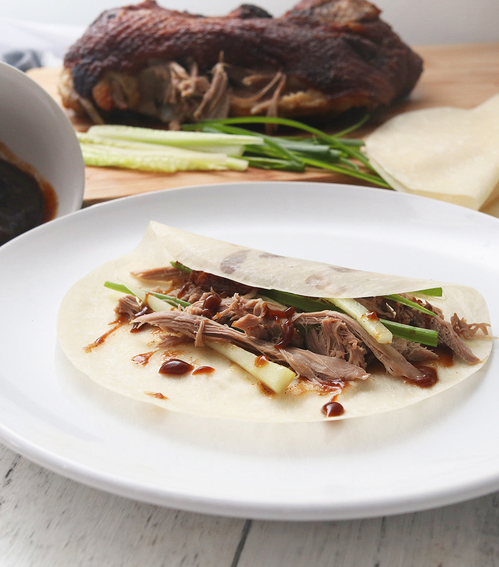 Delicious slices of Silver Hill Crispy Duck meat with cucumber, hoisin sauce and Chinese pancakes on a white plate